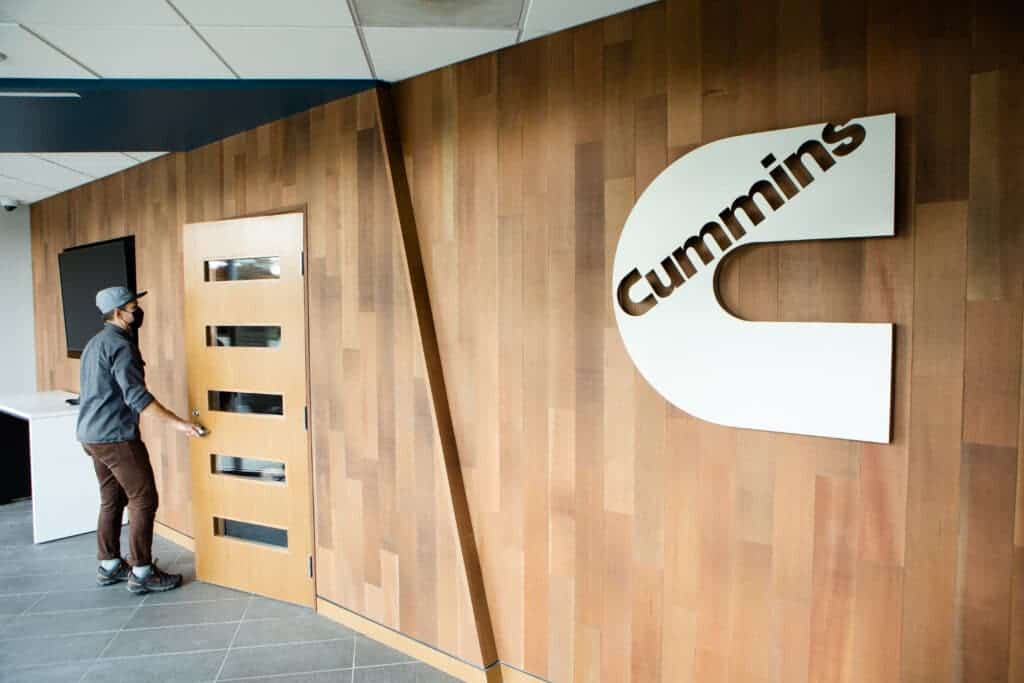 A man is standing in front of the cummins logo.