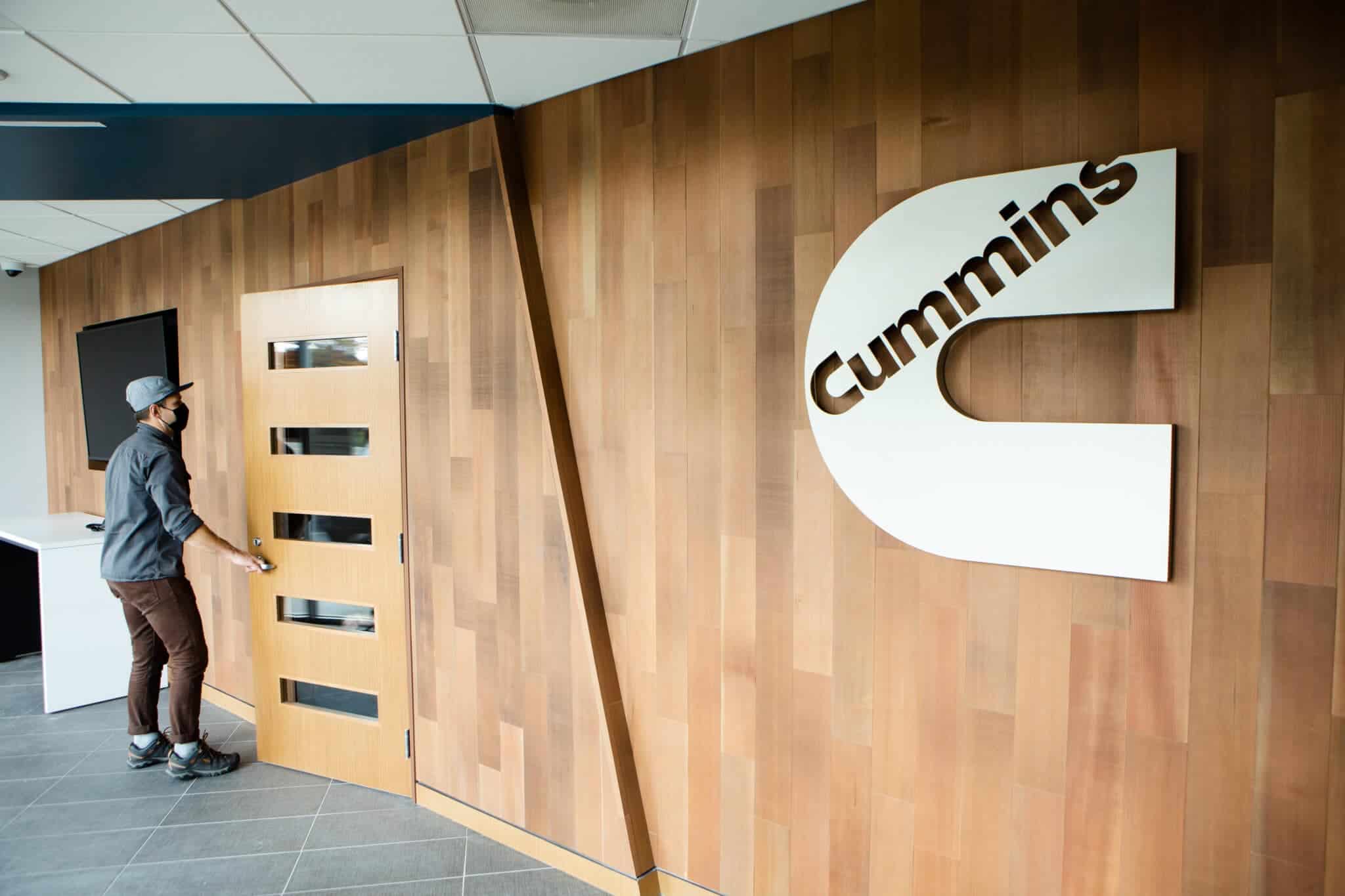 A man is standing in front of the cummins logo.
