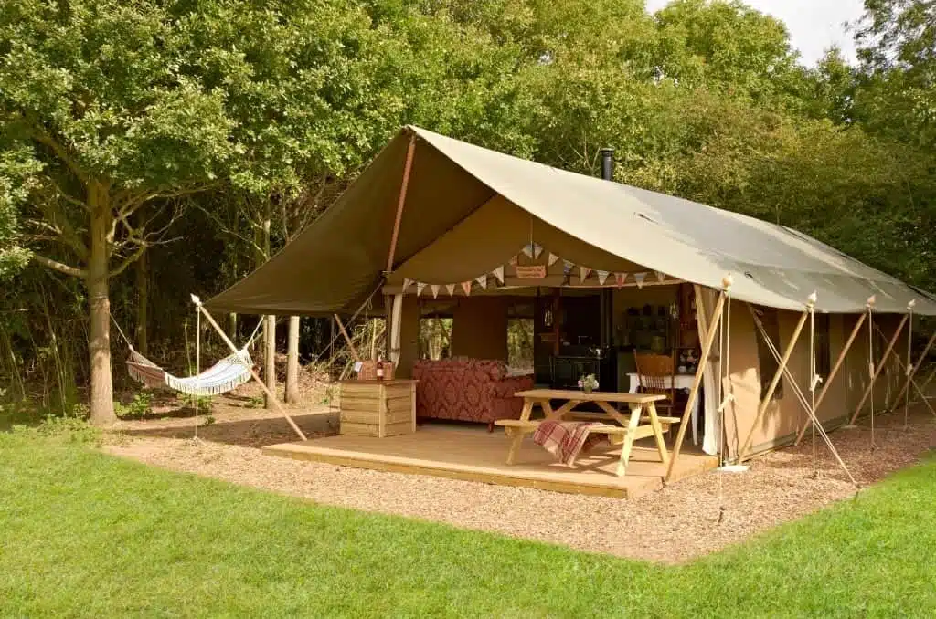 A Suffolk glamping site featuring a large tent in the woods with a hammock.