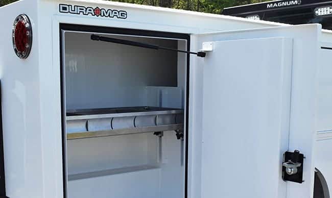 A durable white cargo trailer manufactured by DuraMag, a subsidiary of the Shyft Group, featuring an open door.