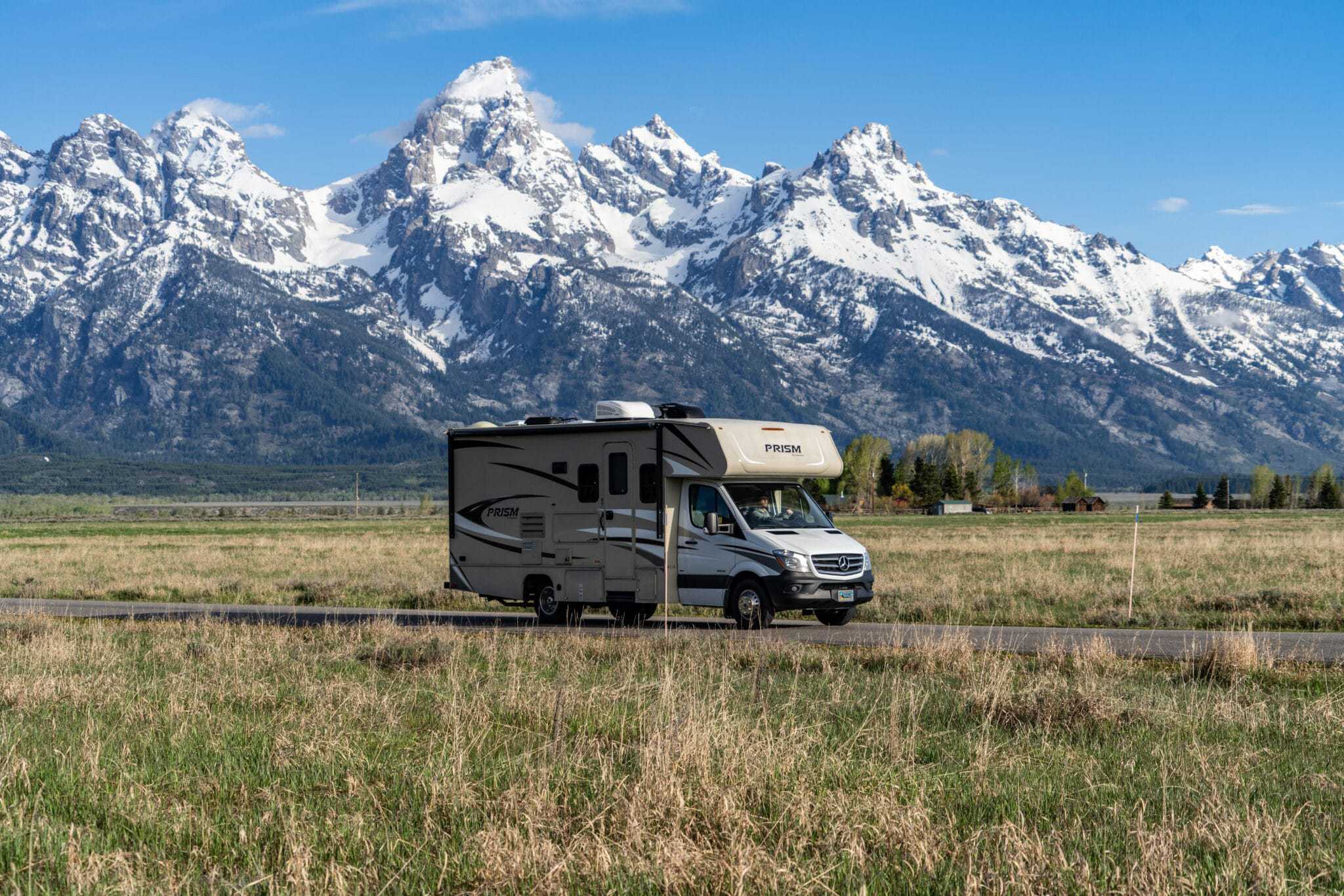 A Dentalcorp RVshare driving down a road with mountains in the background.