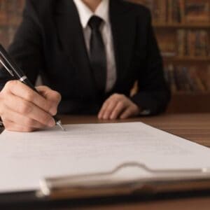A business woman signing a document at a desk to ensure liability protections for campground operators in accordance with House Bill.