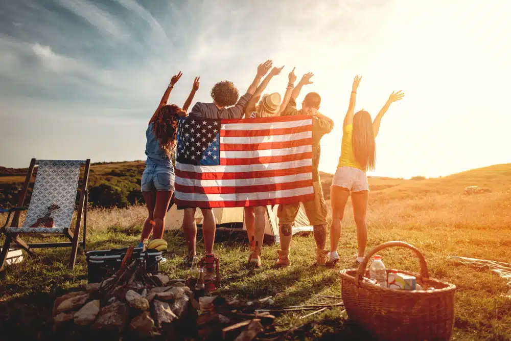 Campers holding an american flag in a field.