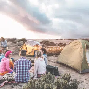 A group of people caravanning in Western Australia, sitting around a tent in the desert.