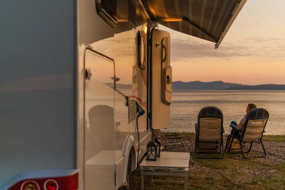 A couple enjoys the sunset outside their RV at an RV Park in Virginia.