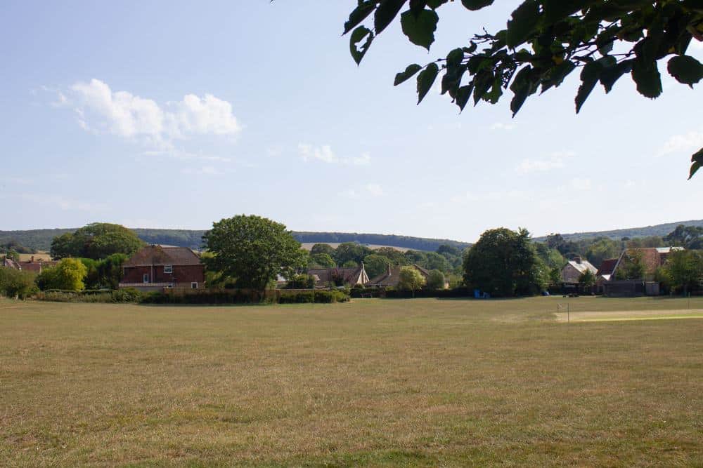 An idyllic Calbourne Farm featuring a glamping experience, with picturesque grassy fields and towering trees in the background.