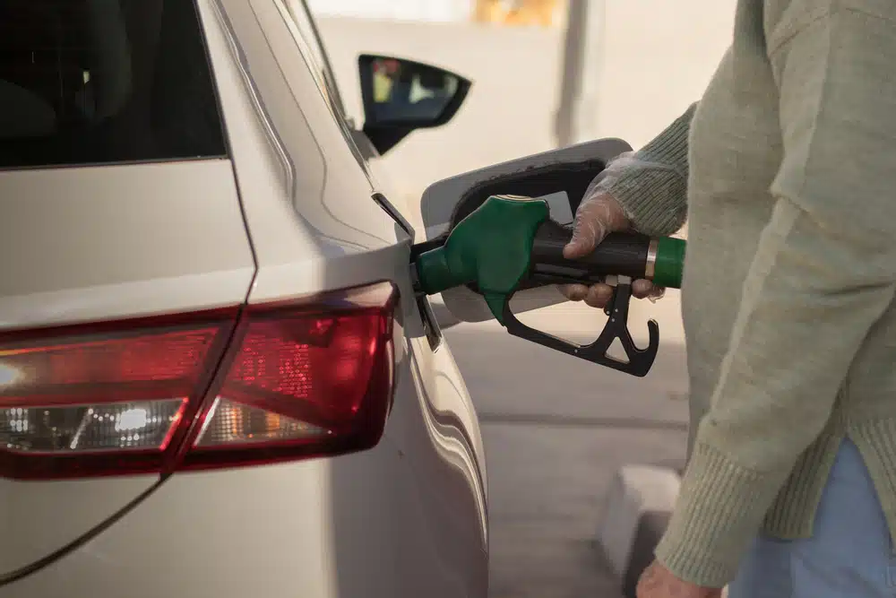 A woman experiencing pain at the pump while filling up her car with gas.