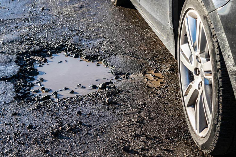 Drivers must navigate carefully around the pothole while their vehicle awaits potential repairs.