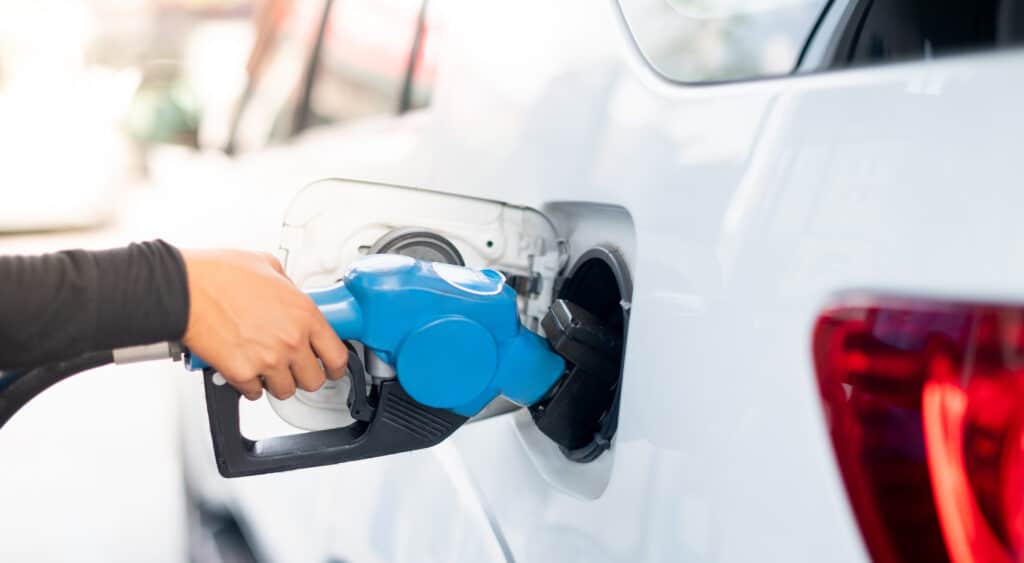 A person filling up a car with fuel while gas prices sink slowly.
