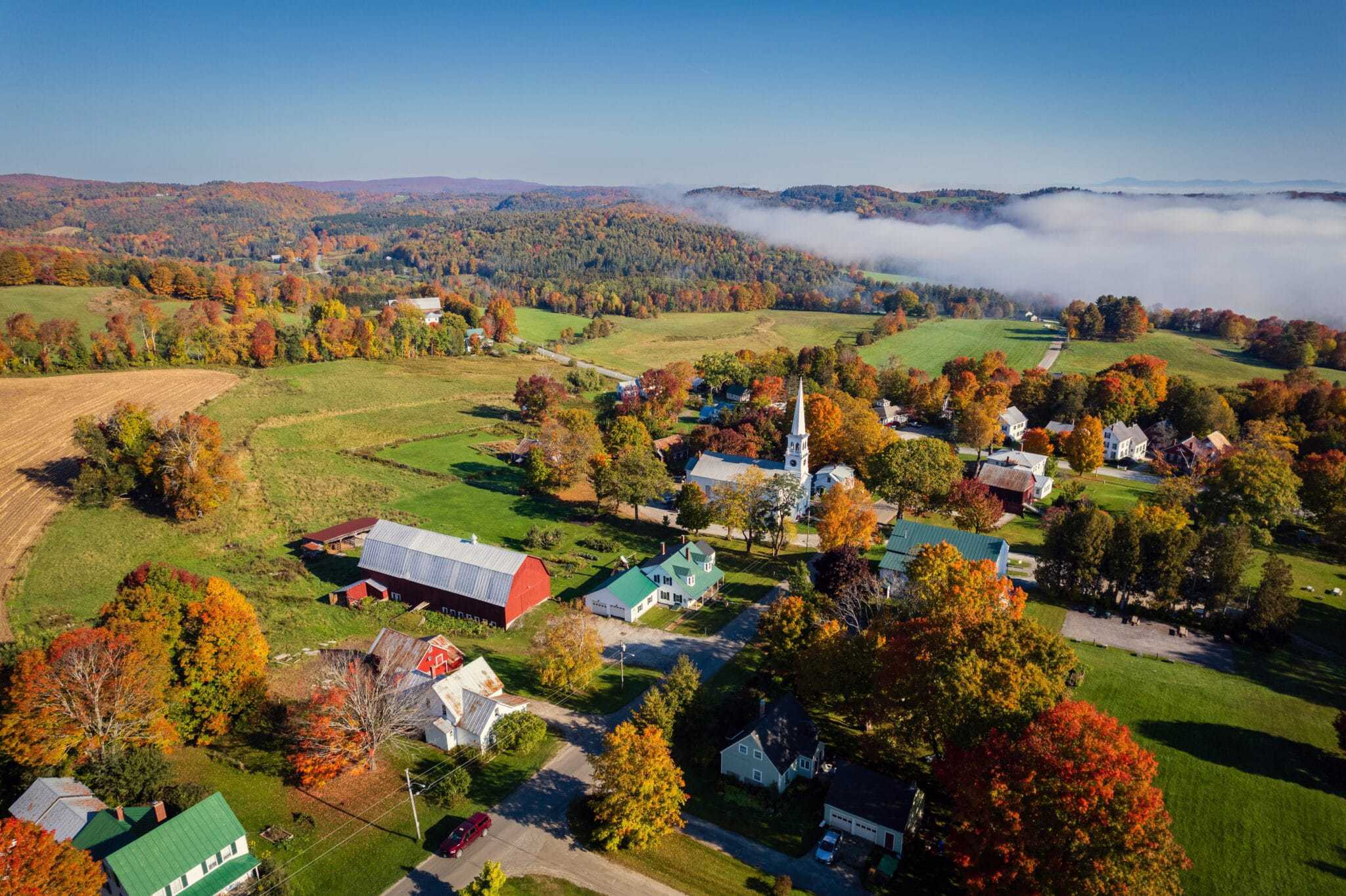 An aerial view of a village in Vermont during the fall season, showcasing the tight-knit community and potential for grants.