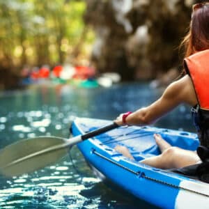 Two women paddling a kayak through a cave during a camping trip at RiverWalk RV Park in North Carolina.