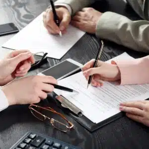 A group of business people signing documents related to previous owner permit violations at a desk at Elk Creek Campground.