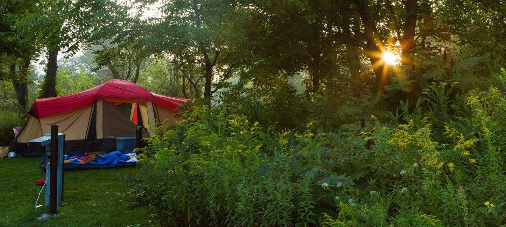 The Blackwell Family Campground offers a serene escape into nature. As the sun dips below the horizon, a tent opens up in the woods, welcoming campers to enjoy a peaceful evening under