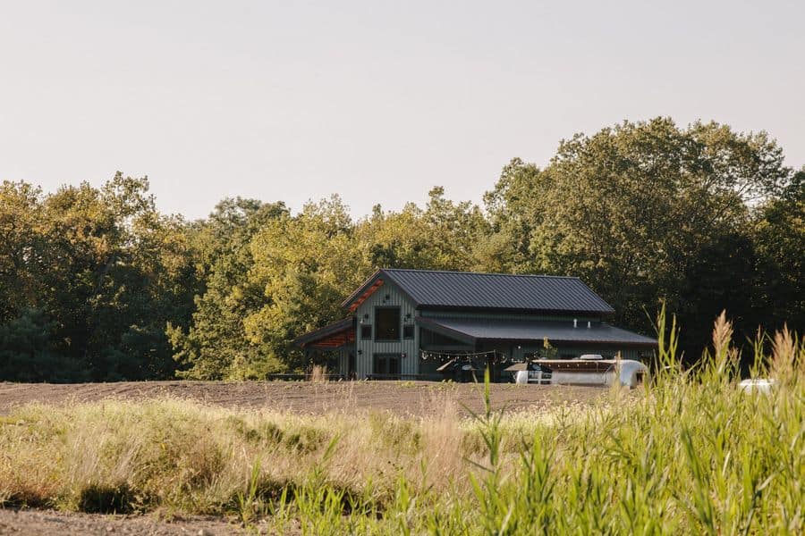 A luxury campground reopens in Illinois, offering a barn nestled in the middle of a field with tall grass.