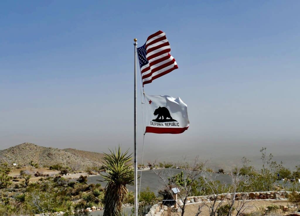 Californians proudly display the California flag as it flutters in front of a majestic mountain, symbolizing their love for their beautiful state.