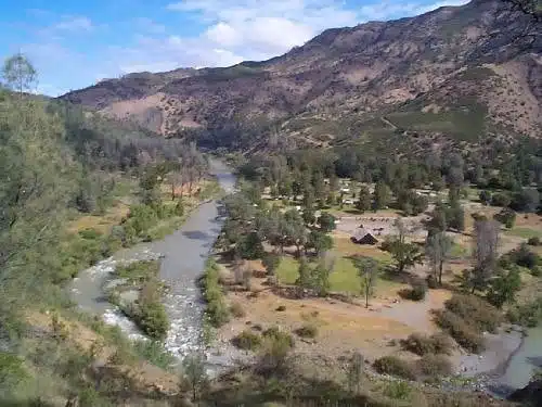 An aerial view of Cache Creek Canyon Regional Park, revealing a stunning river nestled in the mountains during camping season.