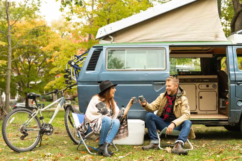 An outdoorsy couple enjoys their time in front of a VW camper van.