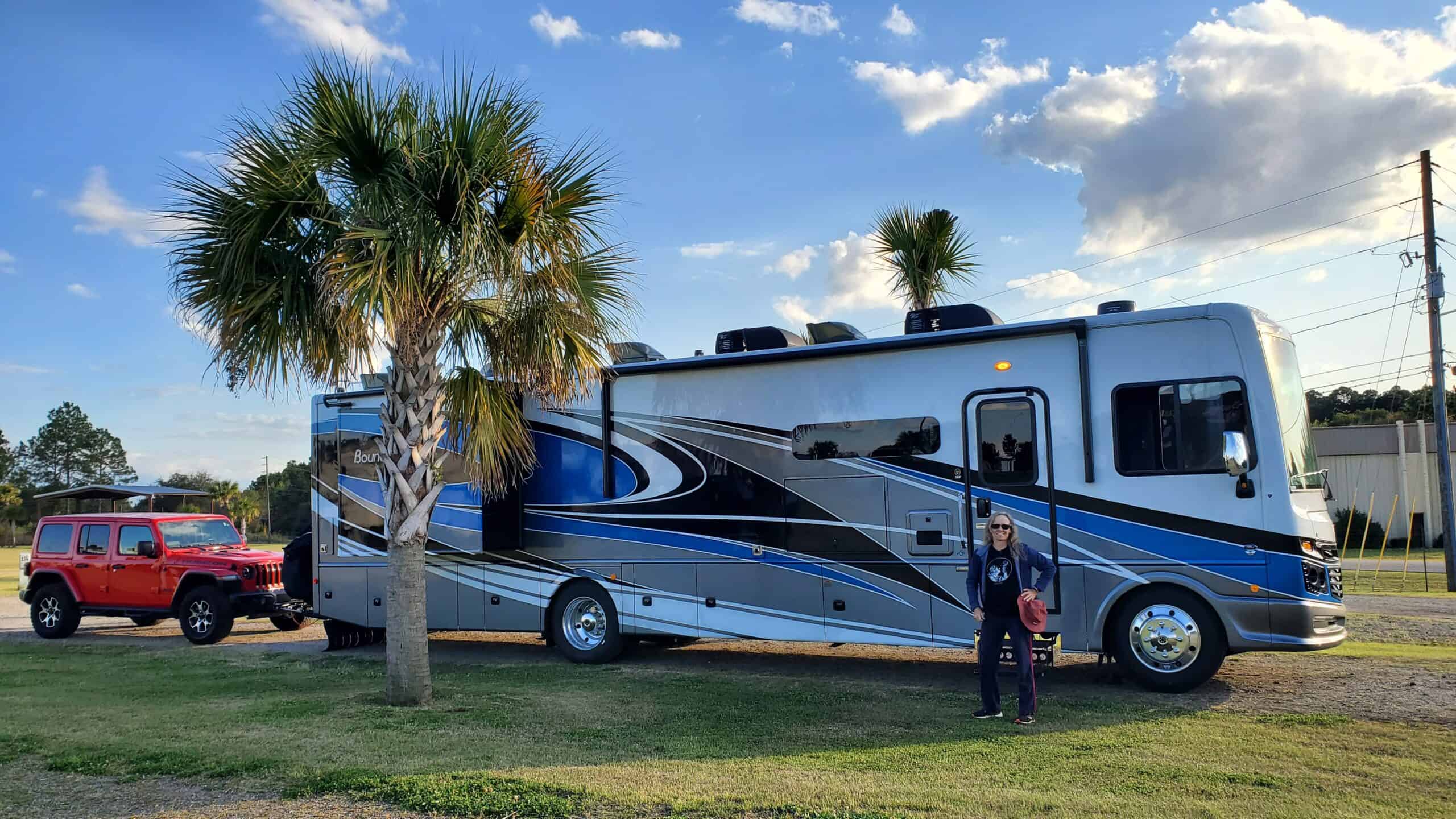 A distracted man standing next to an RV while checking his messages.