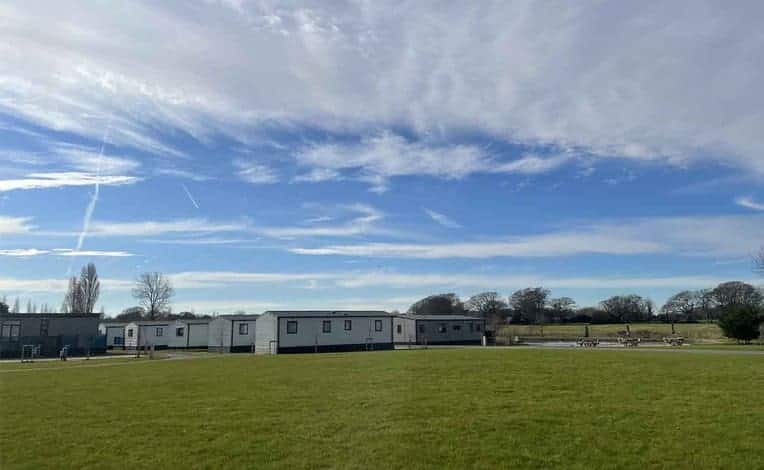 Award-winning holiday park with mobile homes in a field surrounded by a picturesque blue sky.