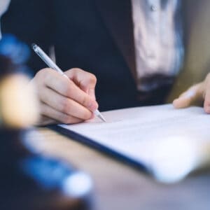 A woman signing a document related to Water Law with a gavel.
