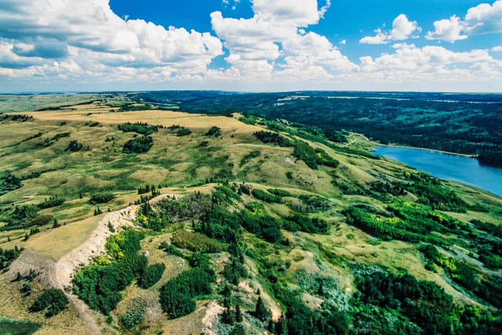 An aerial view of the prairie landscape near Cypress Hills in Saskatchewan, with a serene lake.