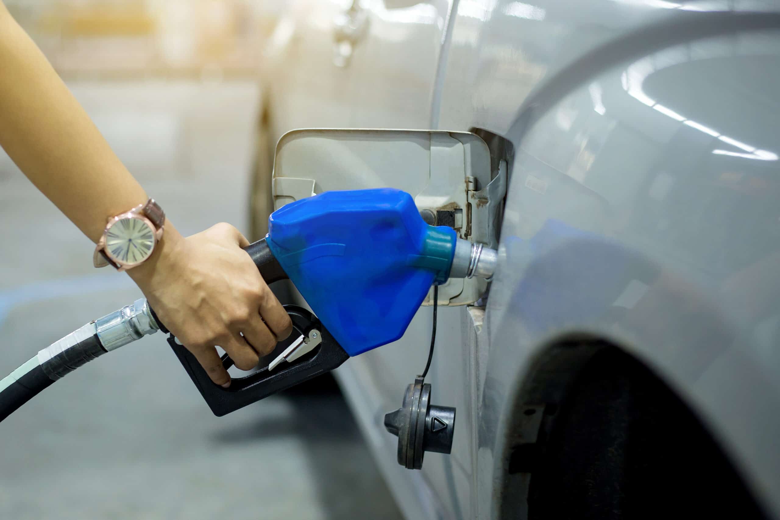 A woman is filling up her car with gas amidst declining gas prices.