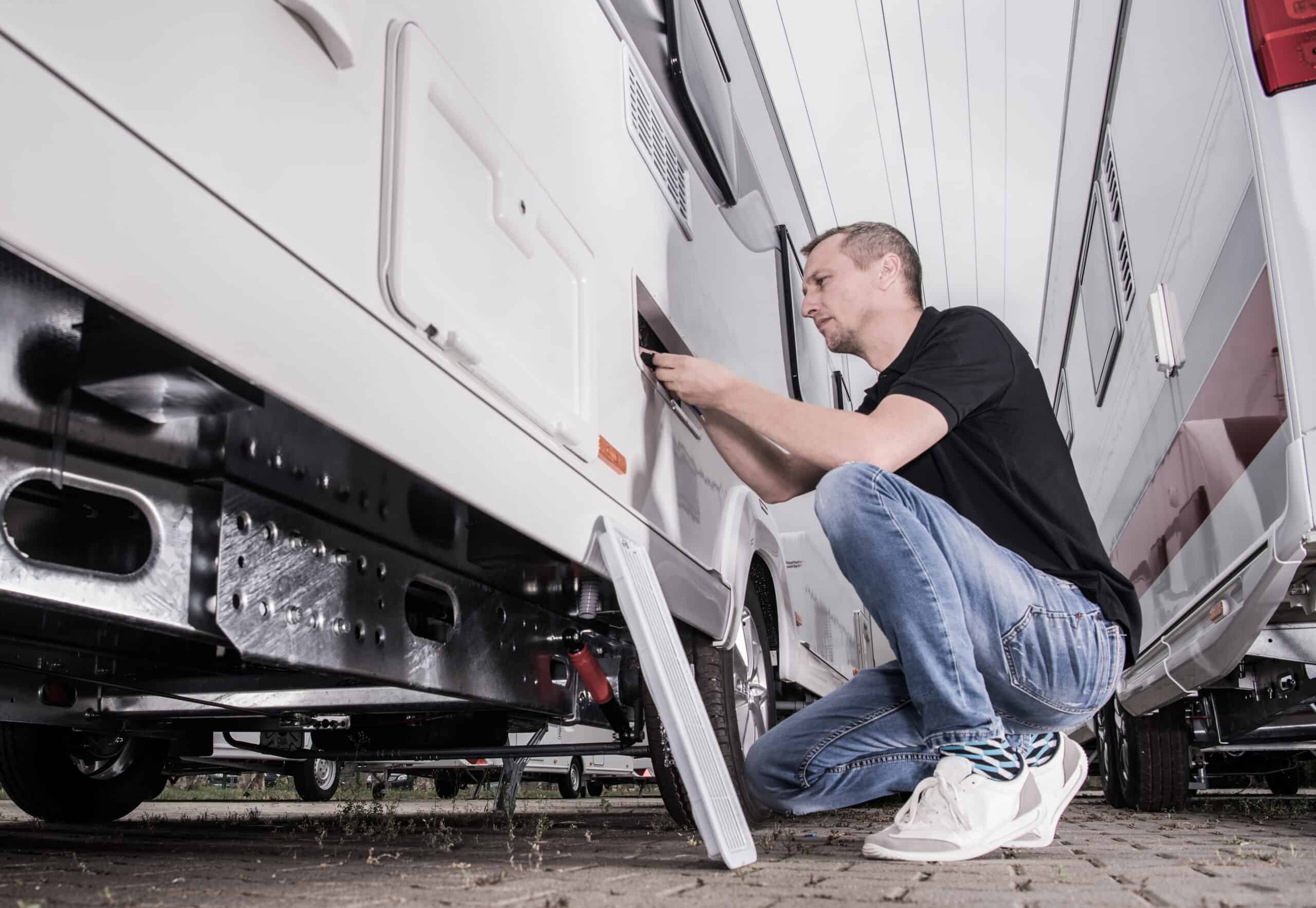 A man participating in the RVTI recruitment program diligently working on an RV in a parking lot during Second Chance Month.