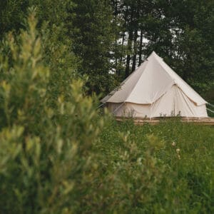 As part of the CampCalNOW Glamping Program, a white tent sits in the middle of a grassy field.