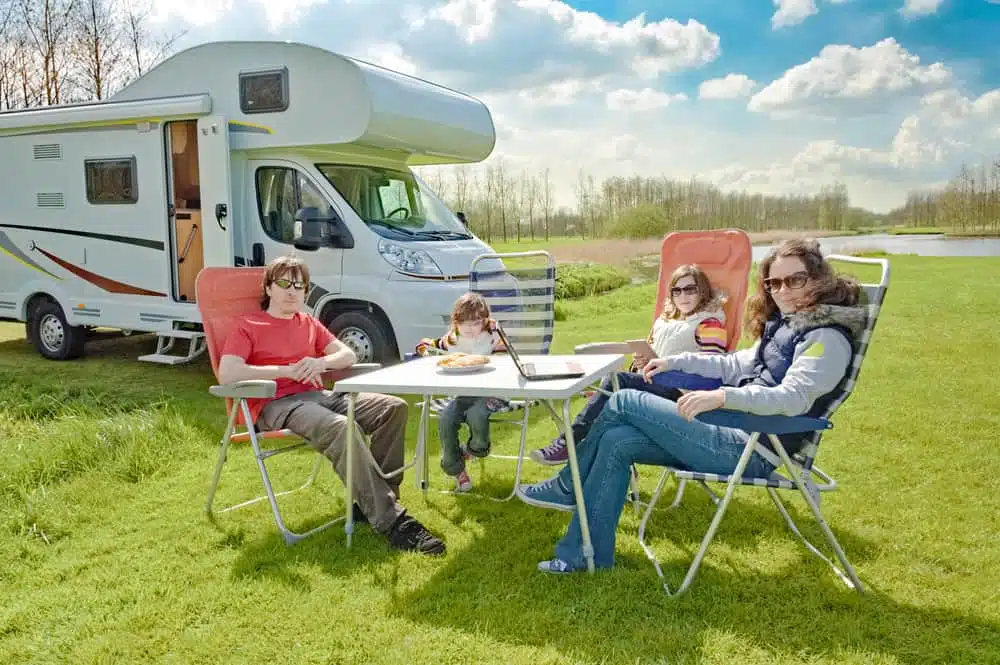 A family enjoys an Easter Holiday at a table in front of an RV during the Victoria Booking Surge.