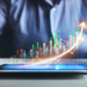 A man is holding a tablet displaying a graph illustrating growth reports.
