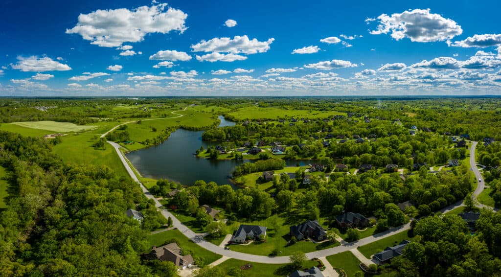 An aerial view of a residential area with trees and a lake in Kentucky.