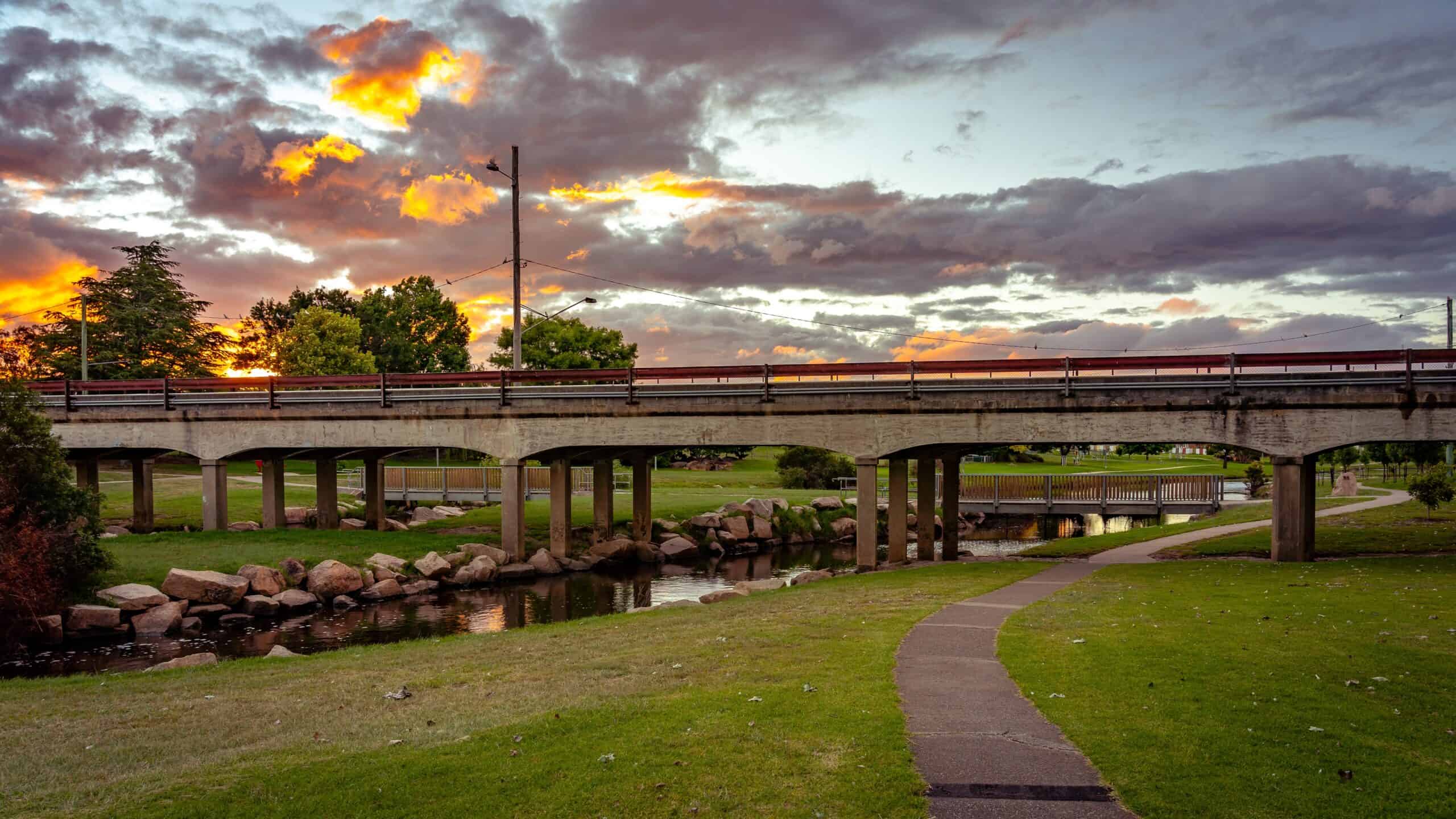 A flood-affected bridge over a river at sunset in Queensland.