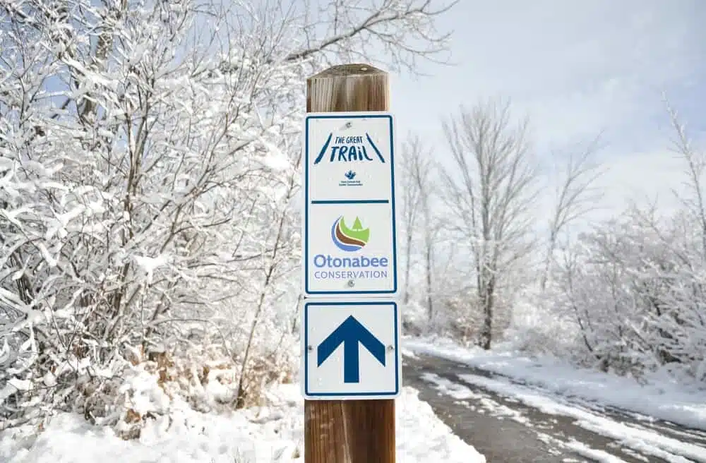 A sign with an arrow pointing to a trail in the snow at Otonabee Conservation Sites.