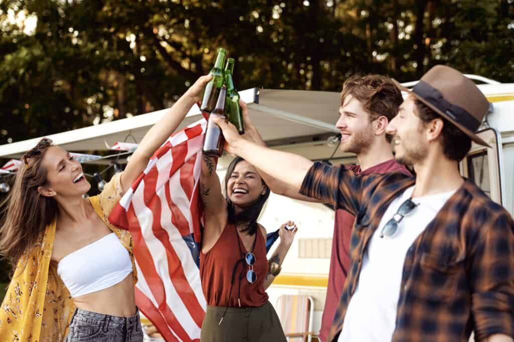 A group of friends holding an American flag and enjoying Visit Indiana Week in front of an RV.
