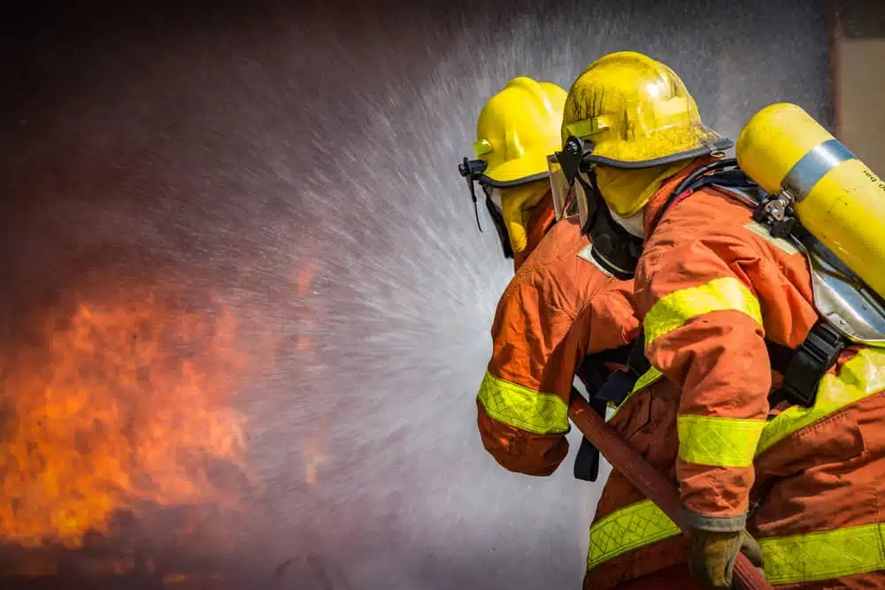 Two fire fighters spraying water in front of a controlled burn in Saskatoon.