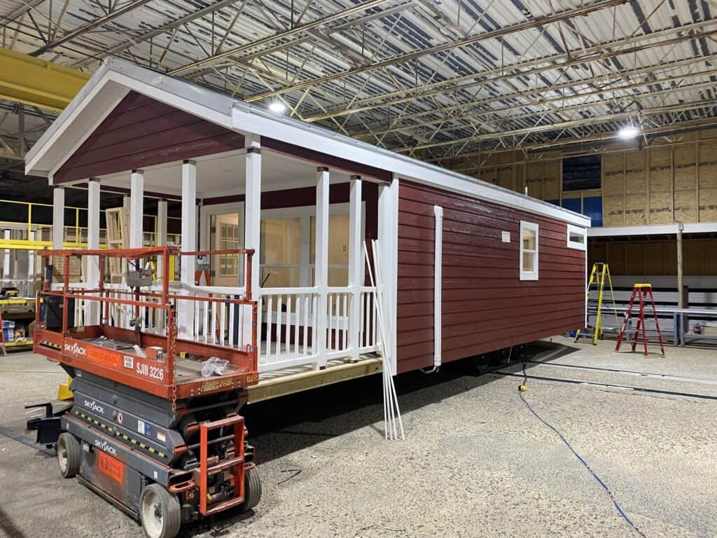 A red and white tiny house is being constructed in a new facility.