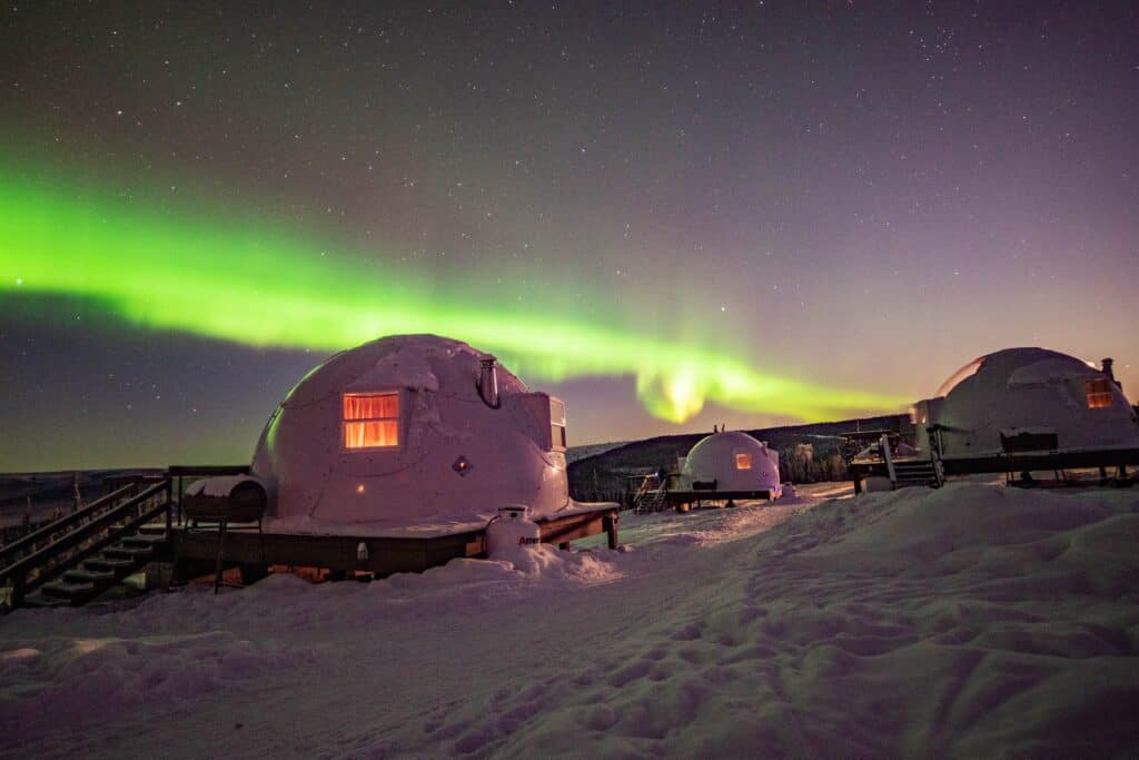 A cluster of luxurious igloo huts nestled under the awe-inspiring aurora borealis.