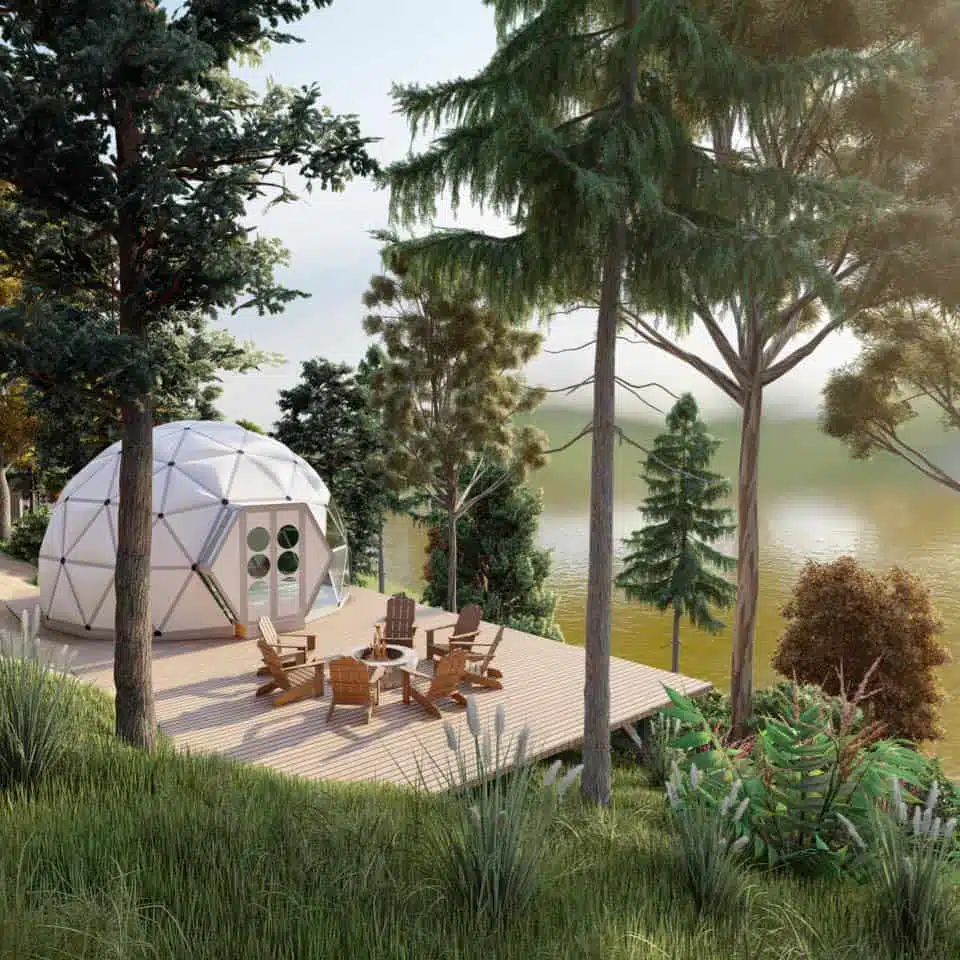 A white igloo tent sits on a wooden deck next to a lake, creating the perfect glamping experience in the southwest.