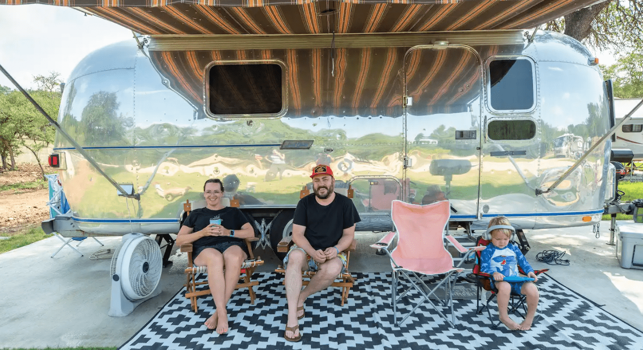 Campers sit in front of an airstream trailer at Camp Fimfo Waco.