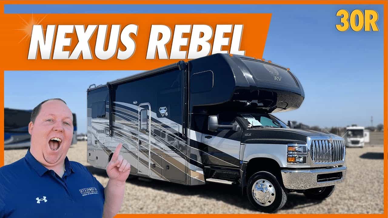 A man is standing in front of the smallest Super C rv with the words Nexus Rebel.