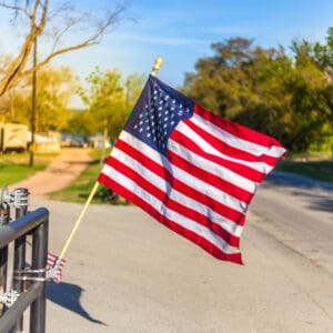 An American flag flies over a fence in a park, commemorating Memorial Day Weekend.