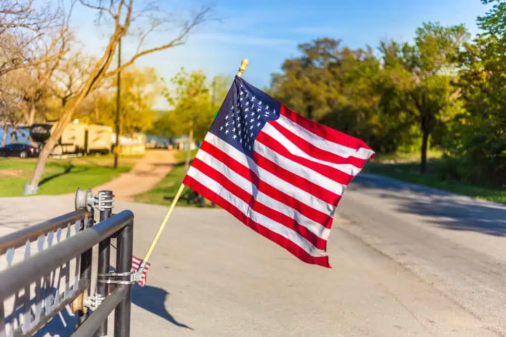 An American flag flies over a fence in a park, commemorating Memorial Day Weekend.