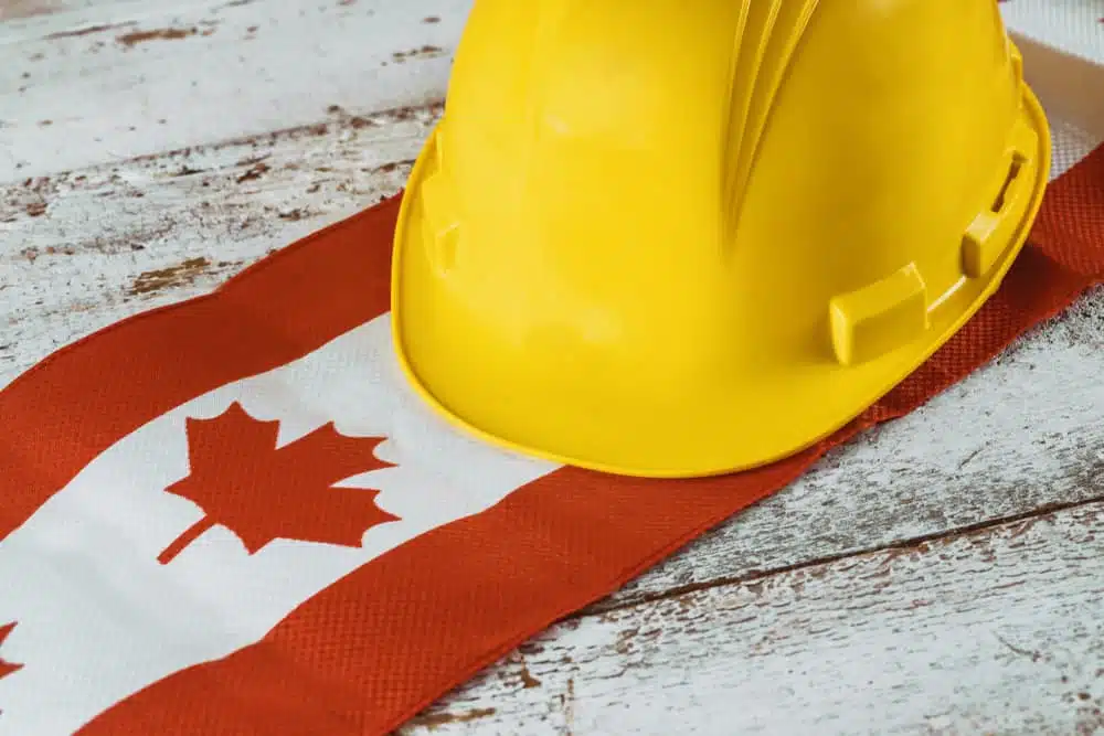 A hard hat and a Canadian flag on a wooden table representing the government's response to the labor shortage.