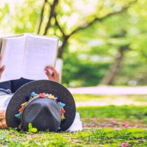 A woman relaxing on the grass, engrossed in a captivating book at a Kansas State Park.