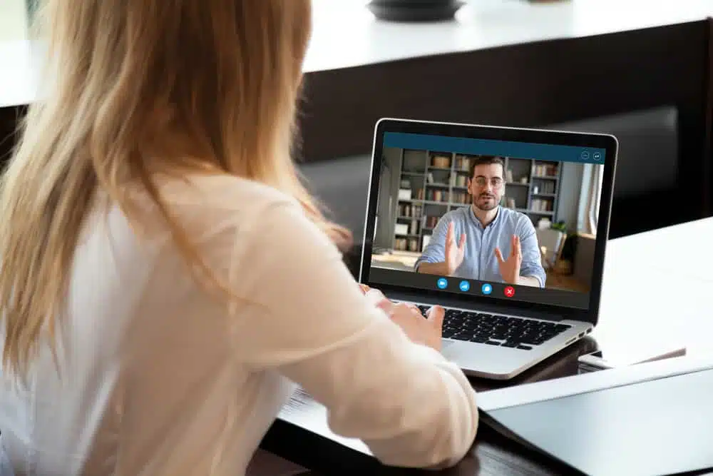 A woman is using a laptop to join a webinar from a campground.