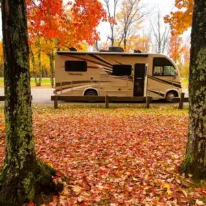 An rv parked in a park with autumn leaves, perfect for a peaceful getaway in Wisconsin Campgrounds.