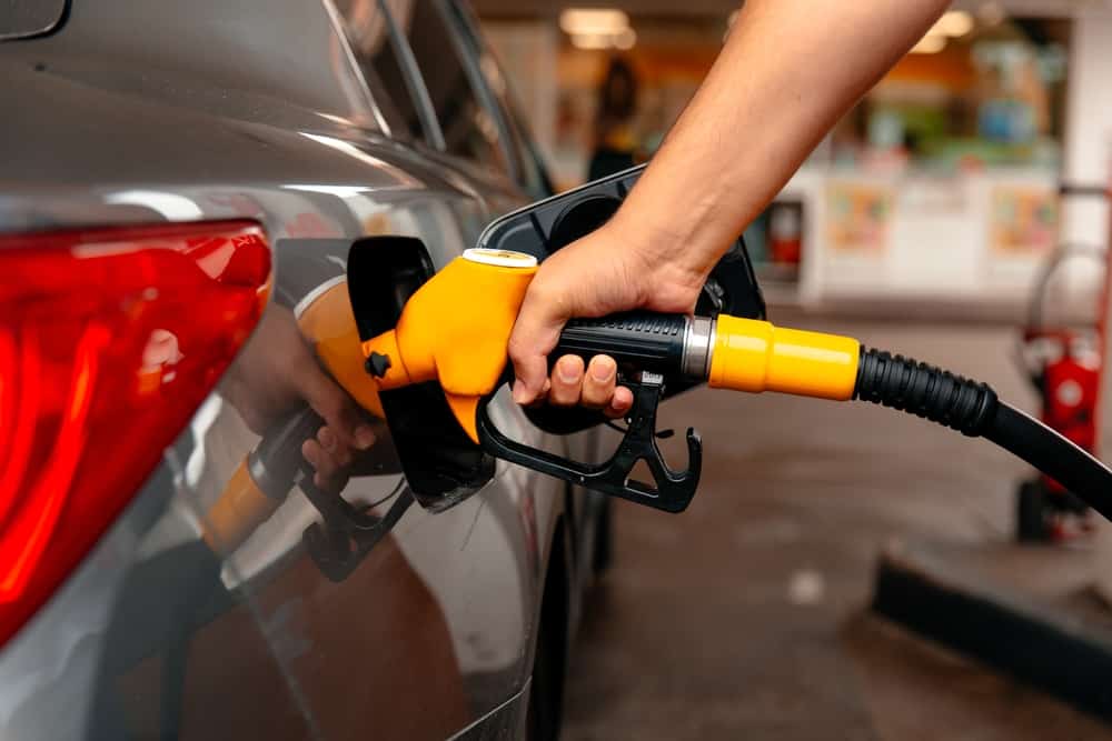 A person filling up a car with gas, concerned about skyrocketing gasoline prices.