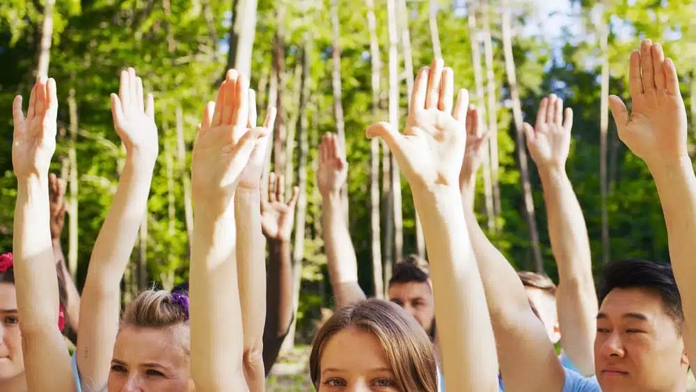 A group of people raising their hands while camping in the forest near Apollo Bay.