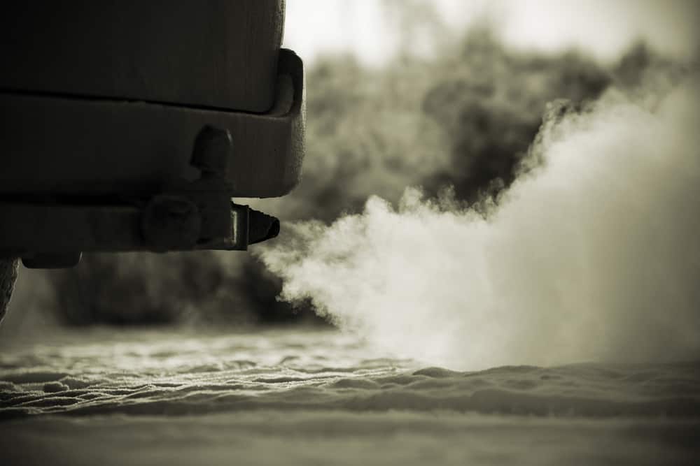 A black and white photo of a heavy-duty vehicle with steam coming out of it.