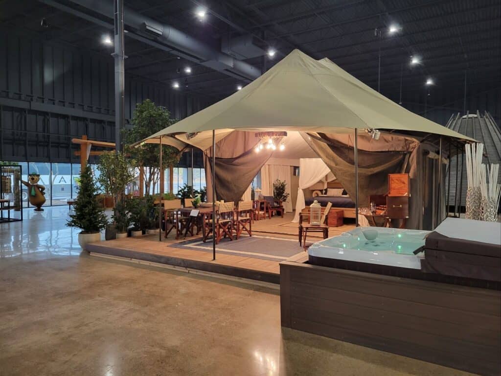 A modern glamping setup featuring a tent with a hot tub inside, perfect for enjoying the sun outdoors.